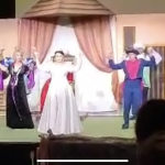 Grupa aktorów tańczy z rękami uniesionymi do góry