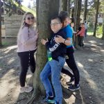 Dziewczynka i dwóch chłopców przytulają się do drzewa