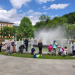 Grupa dzieci bawi się przy fontannie