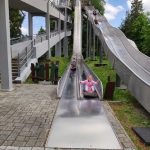 Dziewczynka w różowej bluzie kończy zjazd na ślizgawce