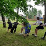 sytuacja przeciągania liny, jedenaścioro uczniów wśród zieleni rywalizuje w przeciąganiu liny.