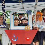 dziewięć osób korzystających z fotobudki, której motywem przewodnim jest tematyka żeglarska i wakacyjna.