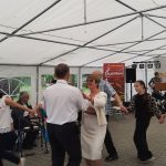 grupa ludzi, którzy tańczą w kółku, na zdjęciu jest grupa około 14 osób.