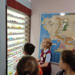 Dwóch chłopców ogląda samochodziki ustawione w wiszącej na ścianie gablocie