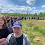 Liczna grupa osób idzie w pielgrzymce przez łąkę