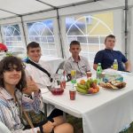 trzej chłopcy i jedna dziewczynka, siedzą przy stole, a na nim ciasta, napoje.