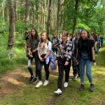 Pięć uśmiechniętych dziewcząt wędruje przez las