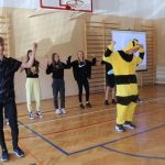 Na scenie chłopiec przebrany za pszczołę, za nim dziewczyny i chłopcy w czarnych strojach, wszyscy trzymają ręce uniesione do góry