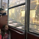 Uczniowie siedząc w kolejce oglądają prezentację mutimedialną