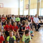 Duża grupa uczniów siedzi na sali gimnastycznej obserwując pokaz