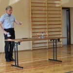 Nauczyciel ogrzewa lampą baterie słoneczne, dzięki czemu karuzela się kręci