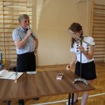 Uczennica zawiesza na równoważni odważniki, pzygląda się temu nauczyciel