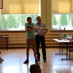 Chłopiec trzyma rurkę, z której wystrzeli kulkę, obok niego nauczyciel