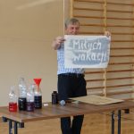 Mężczyzna trzyma w ręce kartkę papieru z napisem: Miłych wakacji