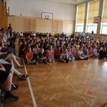 Duża grupa osób zebrana w sali gimnastycznej ogląda pokaz