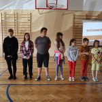 Ośmioro dzieci stoi w rzędzie oczekując na wręczenie nagrody