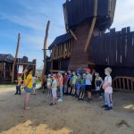 Uczniowie stoją na tle murów obronnych.