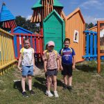 Troje uczniów stoi na tle placu zabaw.