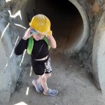 Uczennica z kaskiem na głowie stoi na rozdrożu podziemnego labiryntu.